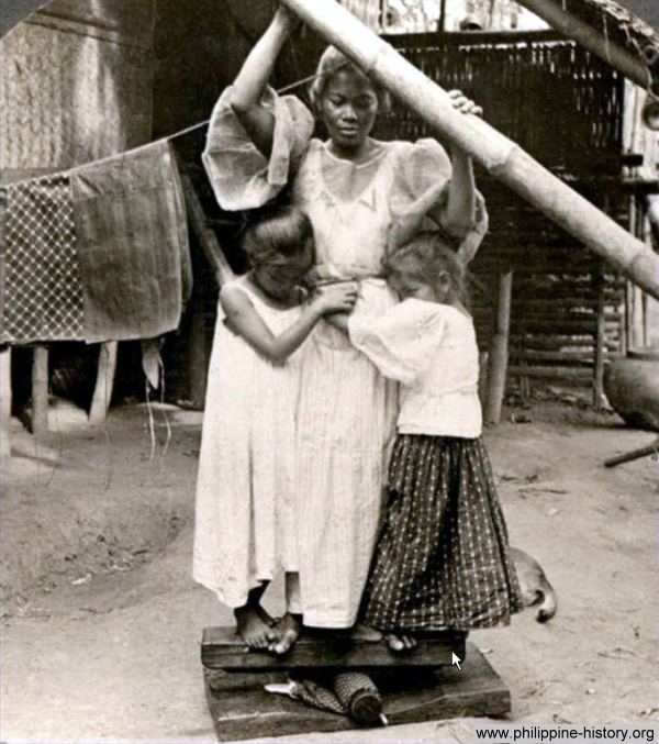 Photo of a woman with two girls ironing clothes circa 1800s. 